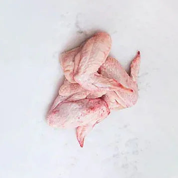 Raw chicken wings offcuts on a white marble surface