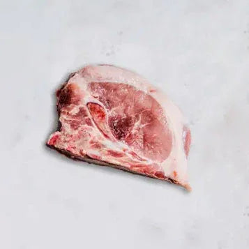 Raw pork chop with bone on white marble surface, fresh uncooked meat slice