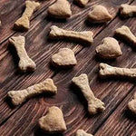 Assorted bone and heart-shaped dog biscuits on a rustic wooden surface