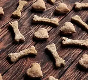 Assorted bone and heart-shaped dog biscuits on a rustic wooden surface
