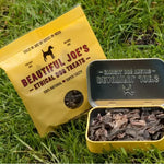 Yellow bag and tin of Beautiful Joe's ethical dog treats on green grass