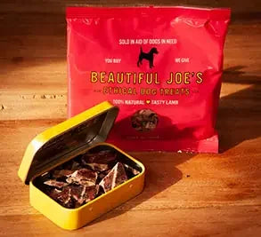 Beautiful Joe's Ethical Dog Treats red bag with open yellow tin of dog treats on wooden surface